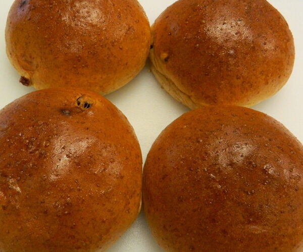 Four golden-brown bread rolls arranged closely on a white surface. The rolls have a glossy finish, indicating they are freshly baked.